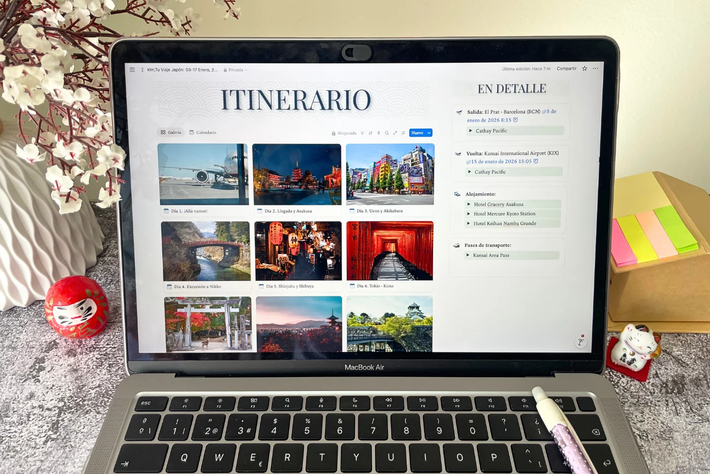 Ordenador con aplicación de viaje e itinerario personalizado a Japón por Oasia Viajes. Con post-its y figuras de maneki neko y daruma.
