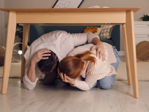 Persona protegiéndose debajo de una mesa durante un terremoto siguiendo las recomendaciones de seguridad en Japón